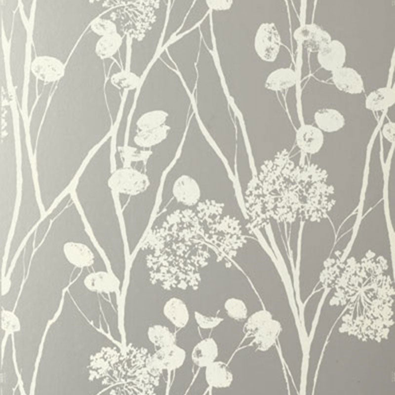 Moonpennies wallpaper in silver by Schumacher, featuring delicate botanical silhouettes on a metallic background, shown in a modern bathroom setting.