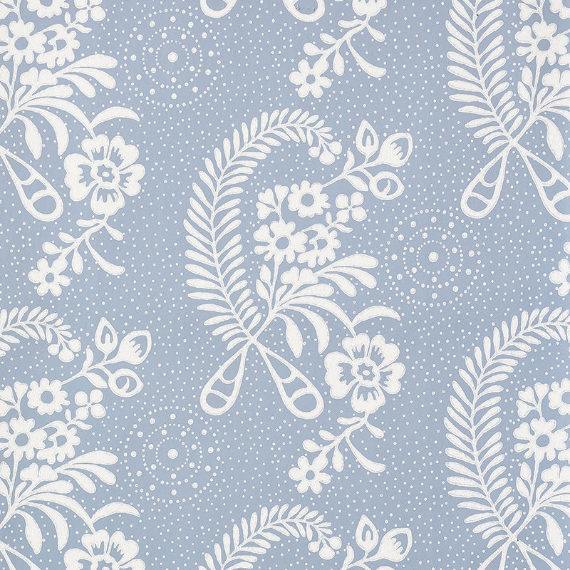 Millicent Delft wallpaper by Schumacher, featuring a delicate white floral and botanical pattern on a blue background, shown in a styled bathroom interior.