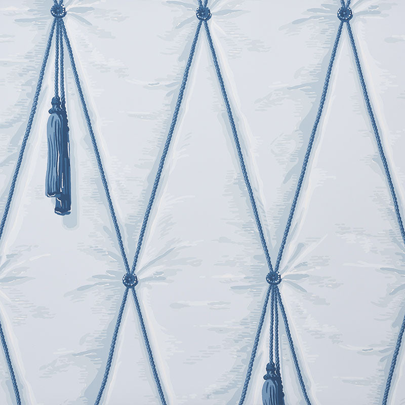 Blue diamond tufted trompe l'oeil wallpaper with hanging tassels by Schumacher, styled in a bedroom setting.