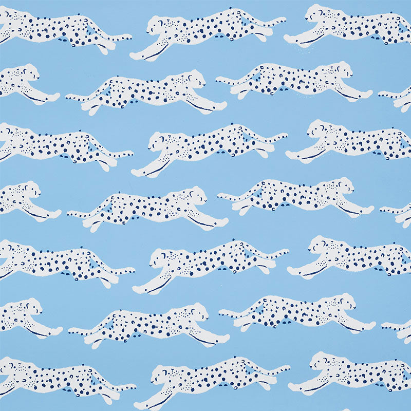 Leaping Leopards wallpaper in Sky by Schumacher features rows of sleek, spotted leopards on a blue background, perfect for adding a lively, chic touch to any room.