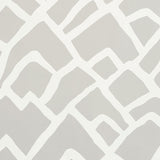 Zimba Fog by Schumacher - abstract hand-printed geometric wallpaper in soft grey and white, shown in a modern living room interior.