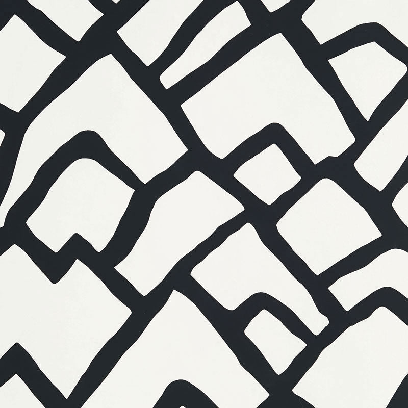 Zimba Ebony hand-printed wallpaper by Schumacher shown in a modern living room interior with bold black and white geometric pattern.