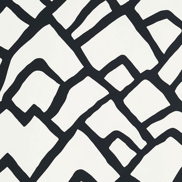 Zimba Ebony hand-printed wallpaper by Schumacher shown in a modern living room interior with bold black and white geometric pattern.