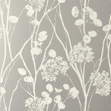 Moonpennies wallpaper in silver by Schumacher, featuring delicate botanical silhouettes on a metallic background, shown in a modern bathroom setting.
