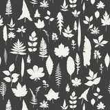 Leaves wallpaper in graphite by Schumacher featuring white botanical leaf silhouettes on a dark background.