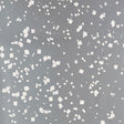 Snow wallpaper in Sterling by Schumacher, featuring a flurry of white dots and squares on a shimmering grey background.