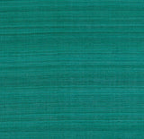 Shaded Silk Peacock wallcovering by Schumacher in a teal blue-green silk texture, shown in a styled interior with a velvet chair.