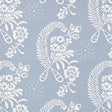 Millicent Delft wallpaper by Schumacher, featuring a delicate white floral and botanical pattern on a blue background, shown in a styled bathroom interior.