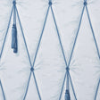 Blue diamond tufted trompe l'oeil wallpaper with hanging tassels by Schumacher, styled in a bedroom setting.