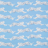 Leaping Leopards wallpaper in Sky by Schumacher features rows of sleek, spotted leopards on a blue background, perfect for adding a lively, chic touch to any room.