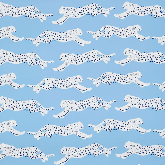 Leaping Leopards wallpaper in Sky by Schumacher features rows of sleek, spotted leopards on a blue background, perfect for adding a lively, chic touch to any room.