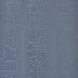 Moire Ocean wallcovering by Schumacher shown in a room setting with a dog on a chair, featuring a watery, irregular blue pattern.