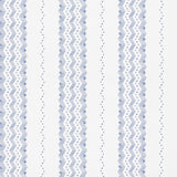 Nauset Stripe Indigo wallpaper by Schumacher, featuring a blue and white zigzag stripe pattern, shown in a modern bedroom setting.