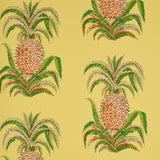 Yellow wallpaper with a repeating pineapple motif and green leaves, inspired by 18th-century Indian design, by Schumacher.