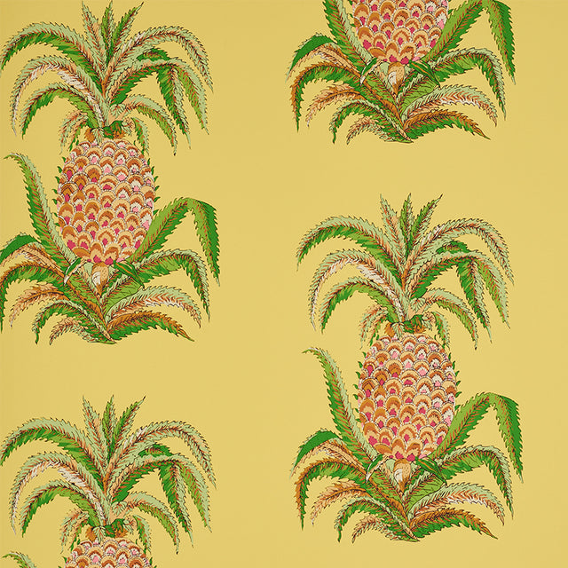 Yellow wallpaper with a repeating pineapple motif and green leaves, inspired by 18th-century Indian design, by Schumacher.