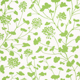 Pennick Leaf on Ivory wallpaper by Schumacher features a painterly green floral silhouette on an ivory background, shown in a bright, airy bathroom setting.