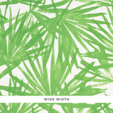 Sunlit Palm green palm leaf watercolor wallpaper by Schumacher shown in a bedroom interior and close-up detail.