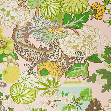 Chiang Mai Dragon Blush wallpaper by Schumacher featuring a vibrant chinoiserie dragon and floral motif in green, yellow, and white on a blush pink background.