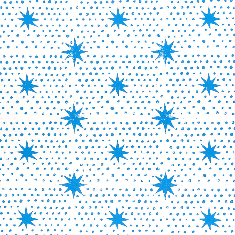Blue dot and star block-print wallpaper by Molly Mahon for Schumacher, shown in a bedroom setting.