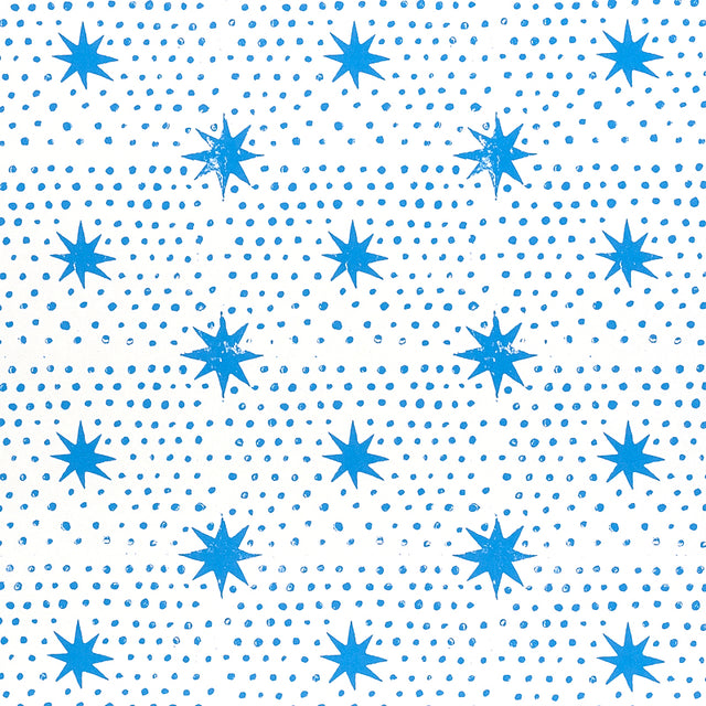 Blue dot and star block-print wallpaper by Molly Mahon for Schumacher, shown in a bedroom setting.