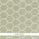 ABACO PAPERWEAVE green hexagonal woven wallcovering by Schumacher, shown in close-up and installed in a bedroom setting.