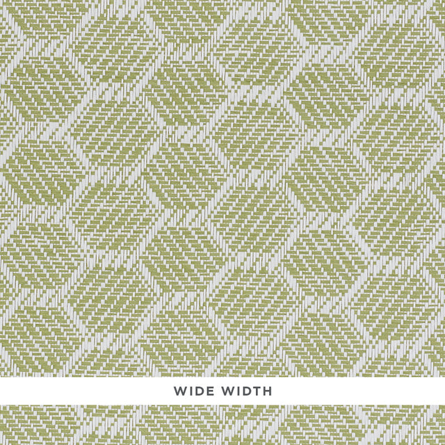 ABACO PAPERWEAVE green hexagonal woven wallcovering by Schumacher, shown in close-up and installed in a bedroom setting.