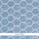 ABACO PAPERWEAVE blue hexagonal woven wallcovering by Schumacher shown in close-up and installed in a bedroom setting.