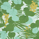 Painterly sea grapes and palm leaves in green and yellow on Schumacher SEA GRAPES wallpaper in Palm colorway, shown in a bright, sunlit room.