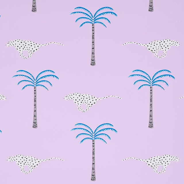 A Wild Desert Dream wallpaper in orchid by Schumacher, featuring playful cheetahs and palm trees on a lavender background.