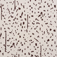 Bespotted brown abstract spotted wallpaper by Schumacher, shown in detail and installed in a modern living room.
