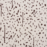 Bespotted brown abstract spotted wallpaper by Schumacher, shown in detail and installed in a modern living room.