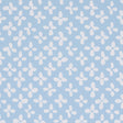 Emerson wallpaper in ivory on sky blue, small-scale quatrefoil-inspired print by Schumacher, shown as a roll and installed in a bright room.