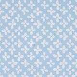 Emerson wallpaper in ivory on sky blue, small-scale quatrefoil-inspired print by Schumacher, shown as a roll and installed in a bright room.