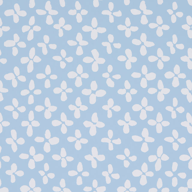 Emerson wallpaper in ivory on sky blue, small-scale quatrefoil-inspired print by Schumacher, shown as a roll and installed in a bright room.