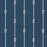 Navy blue wallpaper with vertical white nautical rope stripes and figure-eight knots, styled in a coastal interior setting.